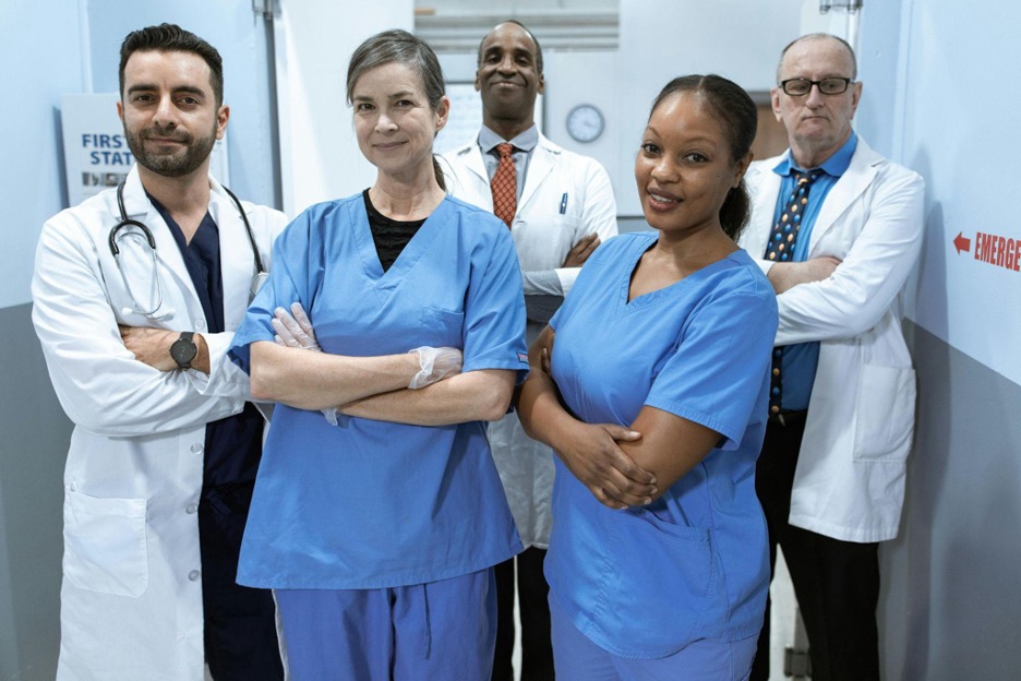 Picture of a diverse group of nurses and doctors standing together in an hall connecting the hospital to the emergency wing