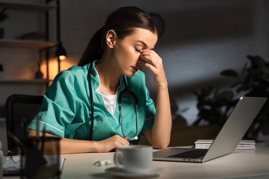 An exhausted nurse finishing work at their desk in a dark room