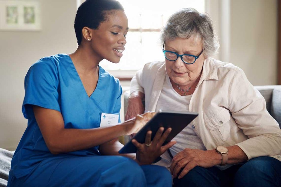 African American nurse reading chart information to elderly white woman in nursing home