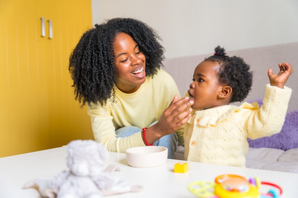 African mother and toddler playing in the living room