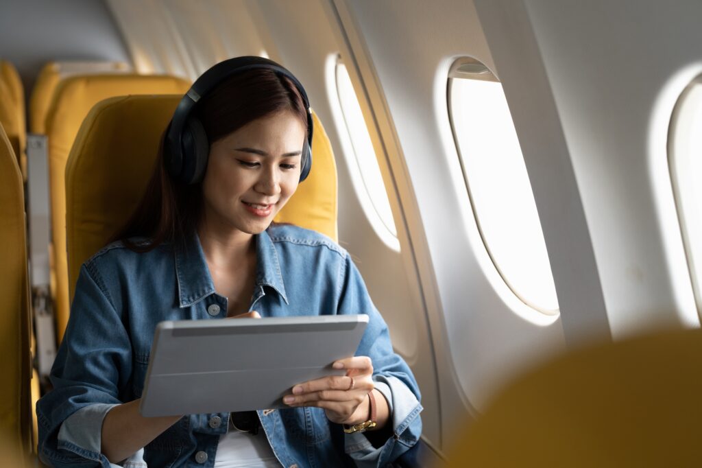 Beautiful asian travel woman watching movie on digital tablet in airplane