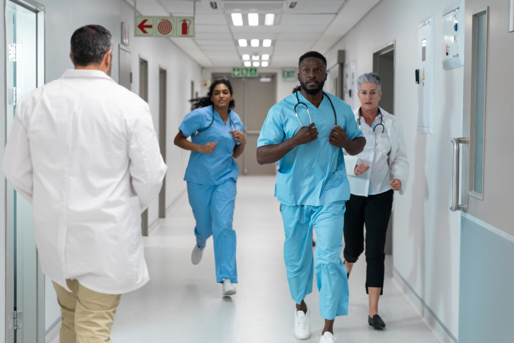 Diverse group of male and female nurses running through hospital corridor