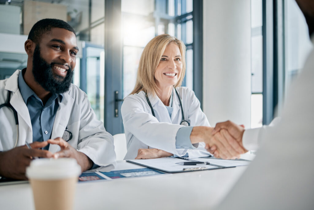 Two Surgeons working out a deal, smiling and shaking hands.