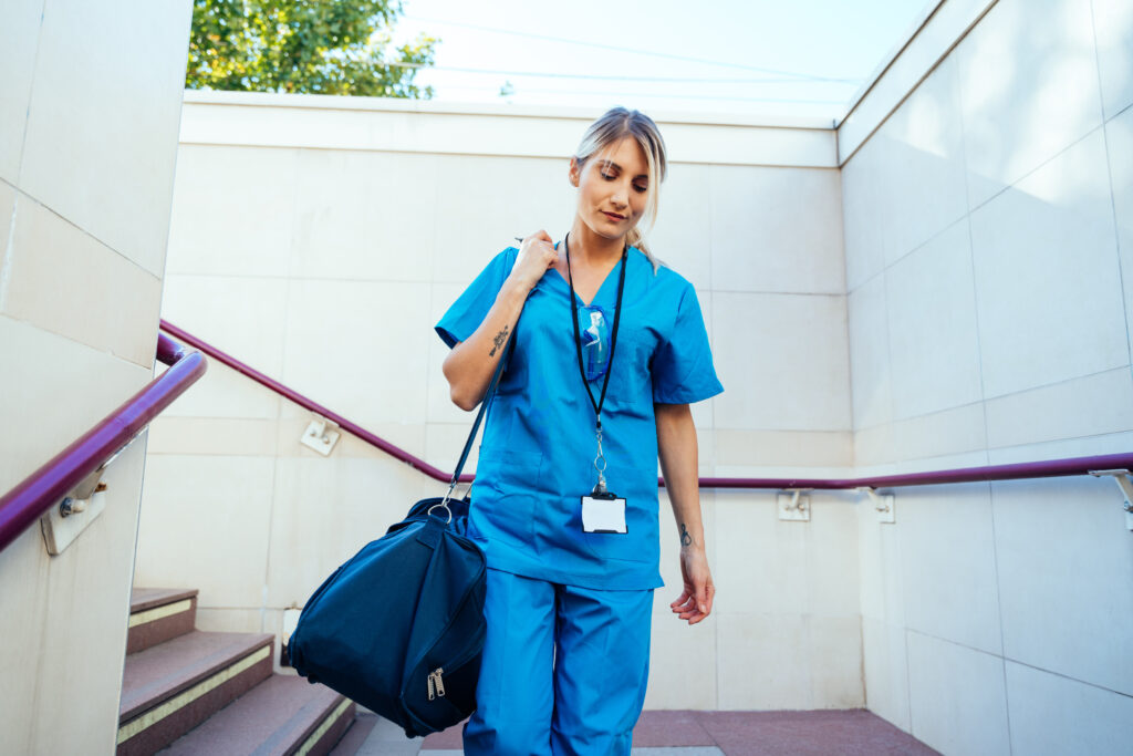 Nurse with belongings walking down steps, traveling to hospital