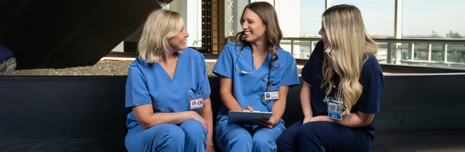 Three female nurses chatting about patient chart and data.