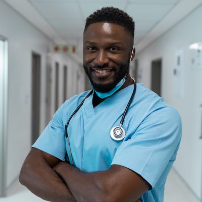 Portrait of african american male doctor wearing face mask standing in hospital corridor medicine health and healthcare services during coronavirus covid 19 pandemic #image_title
